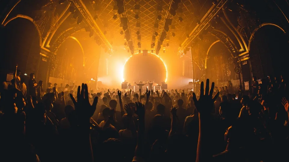 The CLUB GALAME main room before it was torn down: gold light under the arched ceiling and a crowd with their hands up